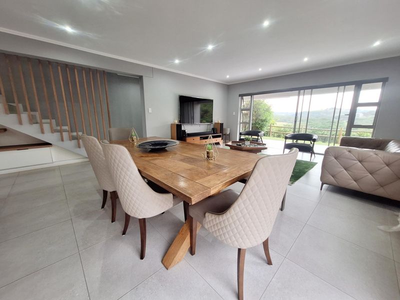 Spacious open-plan living and dining area featuring modern tiled floors, recessed lighting, and large sliding doors opening to a scenic outdoor view.