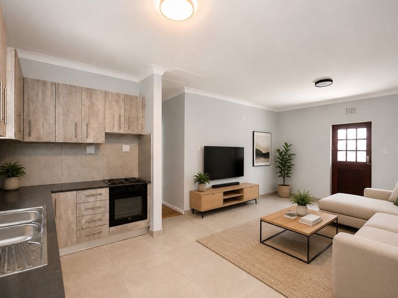 An open-plan living area featuring a modern kitchen with wood-look cabinetry, integrated oven and hob, and a spacious lounge area with direct exterior access.