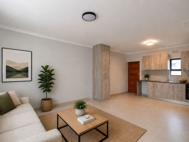 An open-plan living area featuring a modern kitchen with light wood-finish cabinetry, integrated oven, and tiled flooring throughout.