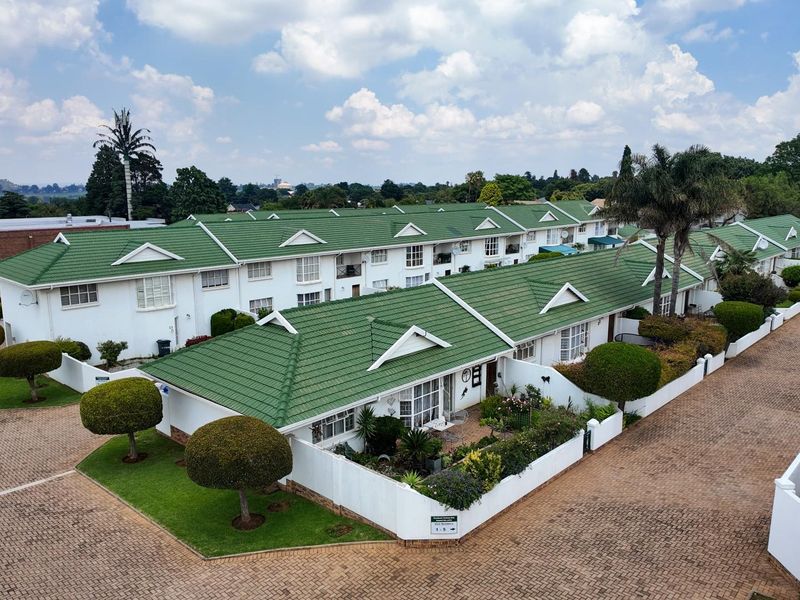 Aerial view of a residential apartment complex featuring green tiled roofs, paved driveways, and well-maintained landscaped gardens.