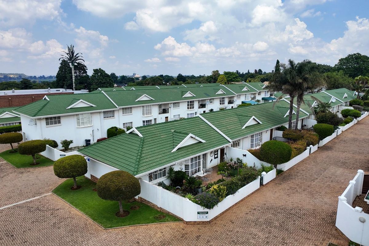 Aerial view of a residential apartment complex featuring green tiled roofs, paved driveways, and well-maintained landscaped gardens.