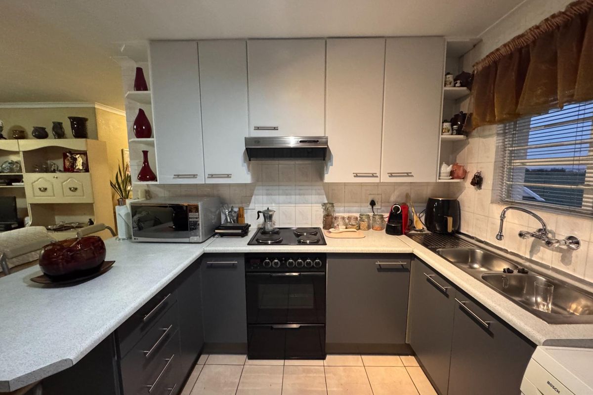 A functional U-shaped kitchen featuring two-tone cabinetry, laminate countertops, a built-in oven with hob, and a double bowl sink.