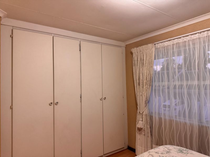 A bedroom featuring built-in cupboards, coving, and laminate flooring, providing functional storage and a neutral base for interior updates.
