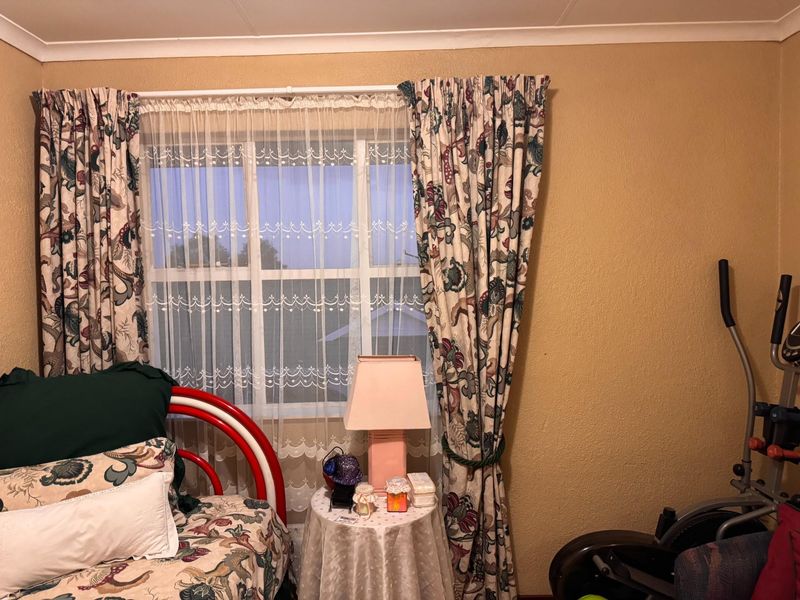 A bedroom featuring a window with decorative curtains and coving, providing a functional space with potential for modern updates.