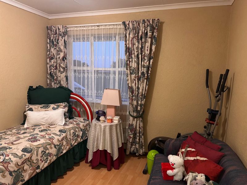 A functional bedroom featuring laminate flooring and a window with curtains, offering a neutral base for potential interior updates.