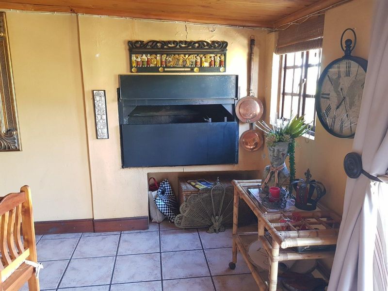 A rustic living area featuring a built-in indoor fireplace, tiled flooring, and timber ceiling beams, creating a cozy and traditional atmosphere.