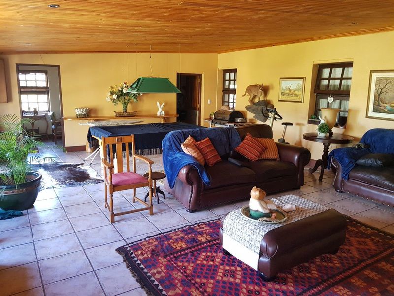 Spacious living area featuring a warm timber-clad ceiling, tiled flooring, and multiple windows providing natural light.