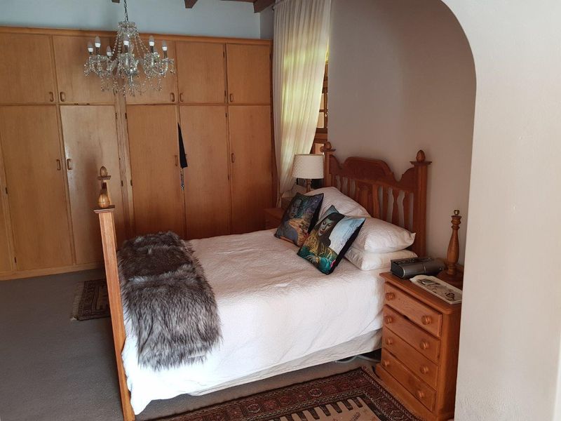 A cozy bedroom featuring extensive built-in wooden cabinetry and exposed ceiling beams, offering ample storage and a warm, traditional aesthetic.