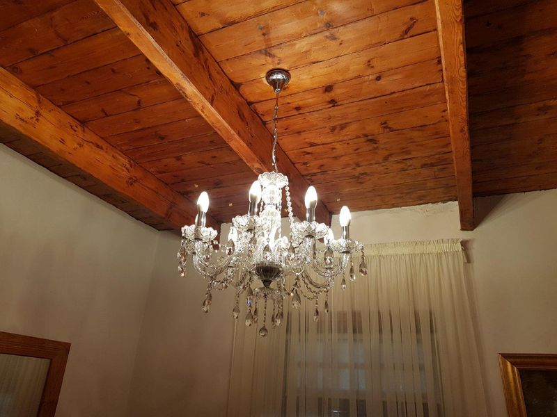 Interior view featuring a rustic exposed timber beam ceiling and a decorative crystal chandelier.