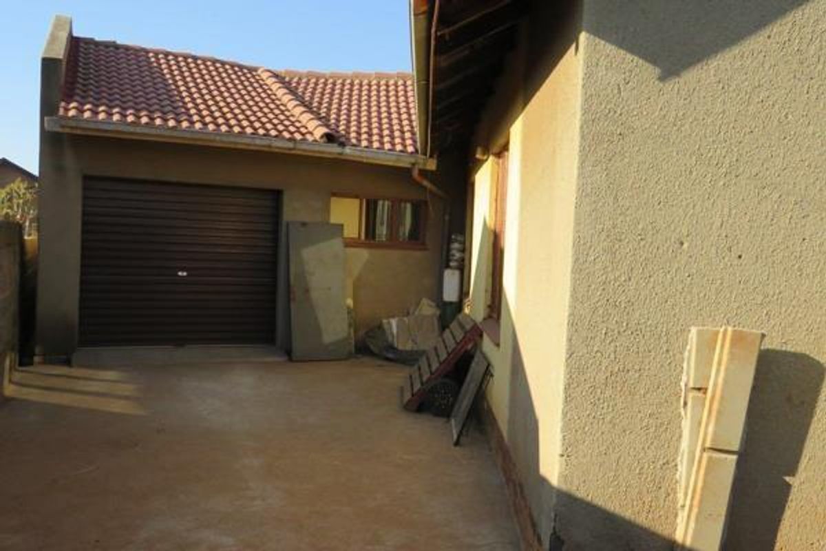 A view of the rear exterior area featuring a single garage with a roller door and a concrete driveway.
