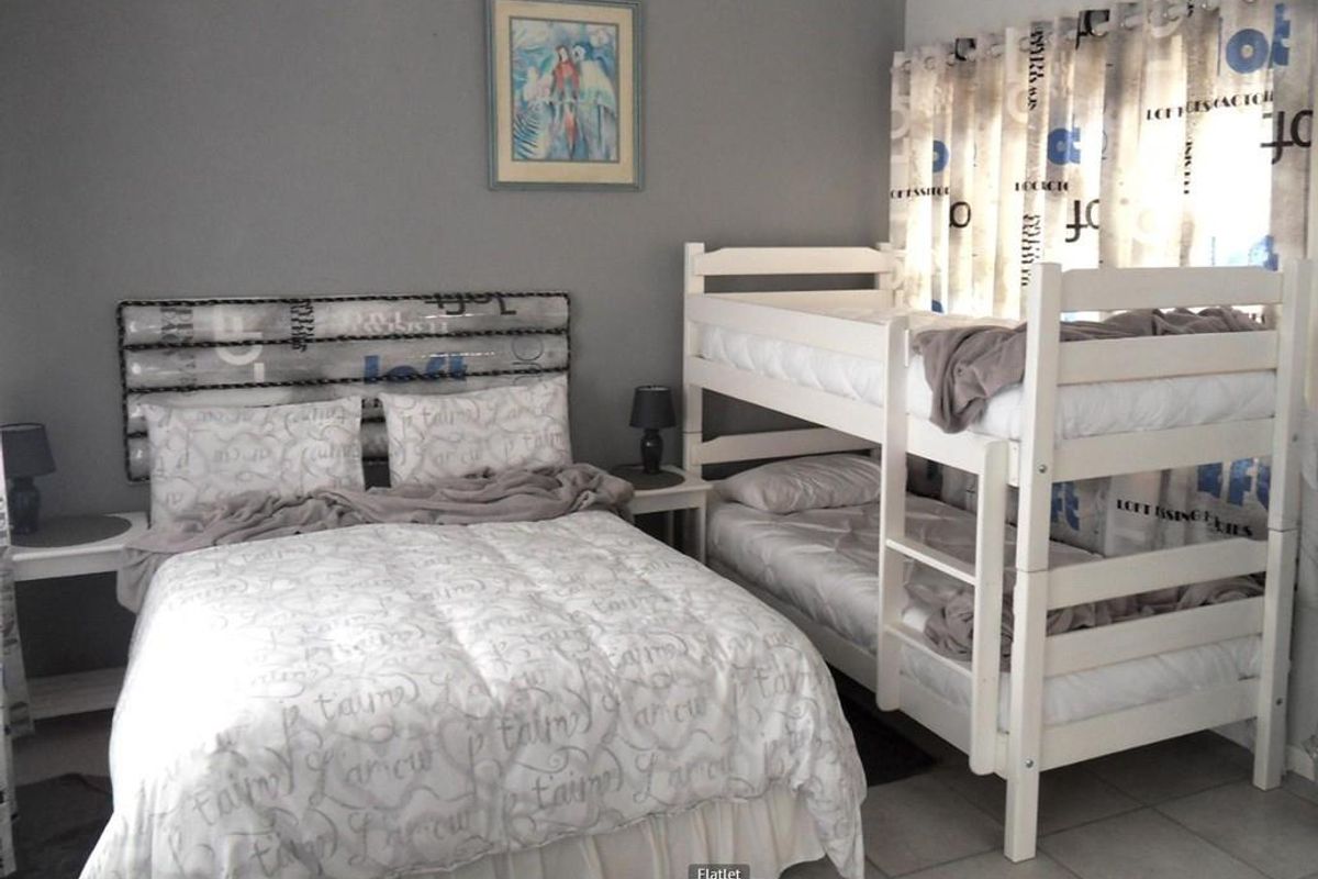A functional bedroom featuring tiled flooring and neutral wall finishes, currently configured with a double bed and a bunk bed setup.