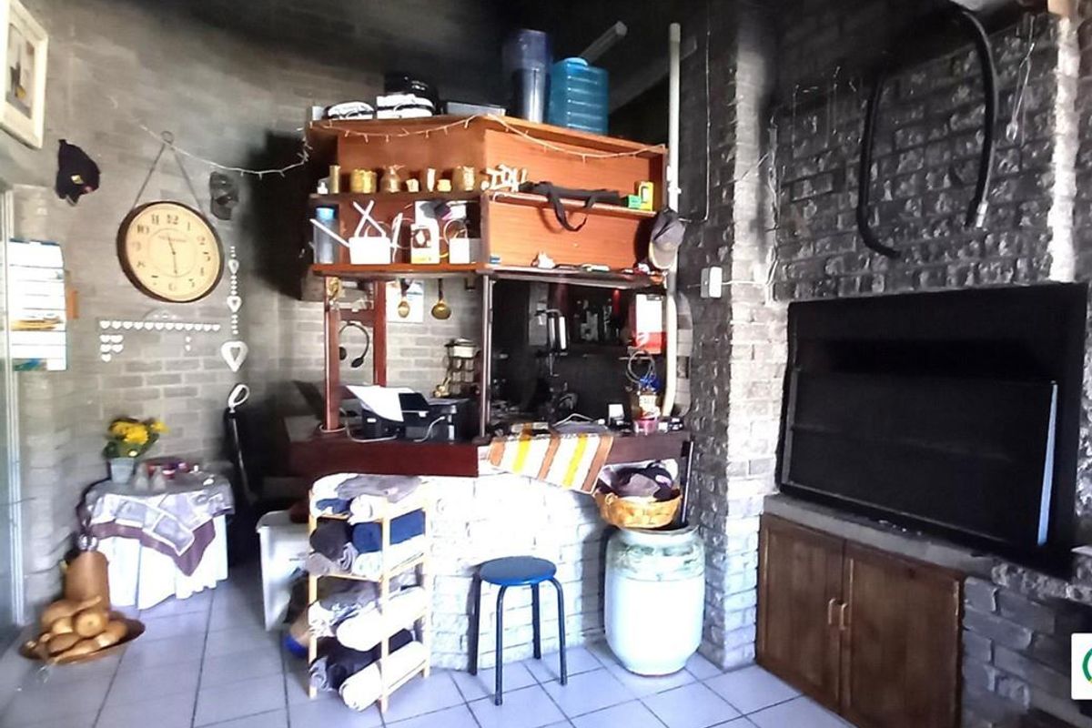 An indoor entertainment area featuring a built-in brick braai, a bar counter, and tiled flooring, offering a rustic space for social gatherings.