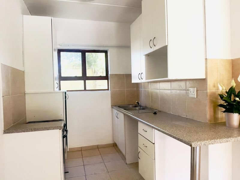 A functional kitchen featuring white cabinetry, laminate countertops, tiled backsplash, and tiled flooring, offering a clean and practical workspace.
