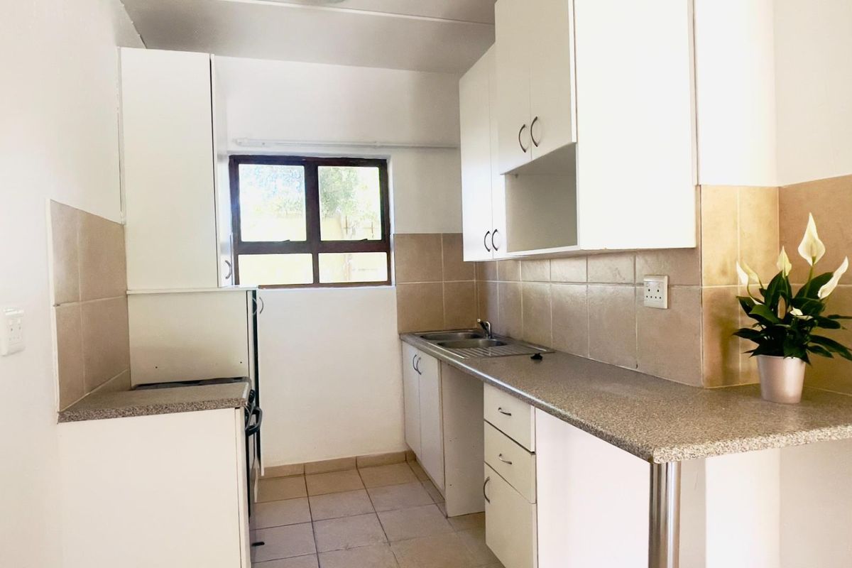 A functional kitchen featuring white cabinetry, laminate countertops, tiled backsplash, and tiled flooring, offering a clean and practical workspace.