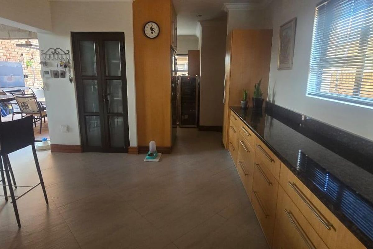 A functional kitchen area featuring dark granite countertops, wooden cabinetry, and tiled flooring, with an open transition to an outdoor patio space.
