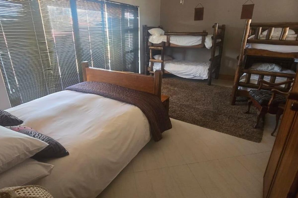 Spacious bedroom featuring tiled flooring and large sliding glass doors with fitted blinds, providing ample natural light and access to the exterior.