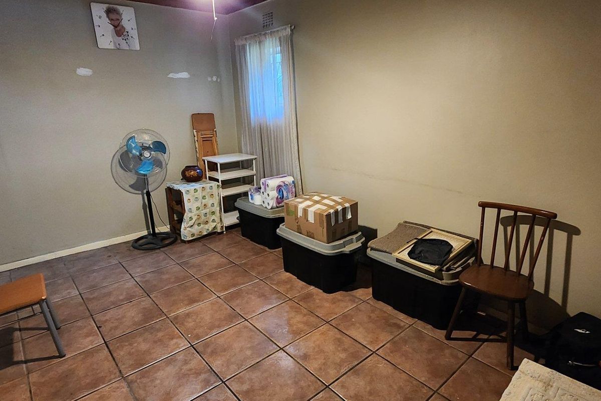 A bedroom featuring tiled flooring and plain walls, currently used for storage. The space requires cosmetic updates to improve its overall appeal.