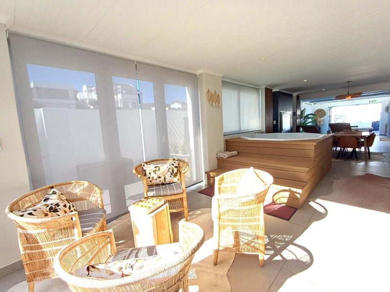 Spacious covered patio area featuring a built-in raised spa bath, tiled flooring, and large glass sliding doors leading to the main living space.