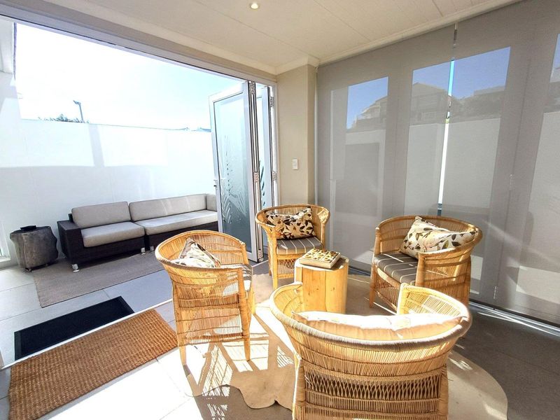 A bright, covered patio area featuring large glass stacker doors that open onto an outdoor seating space, creating a seamless indoor-outdoor flow.
