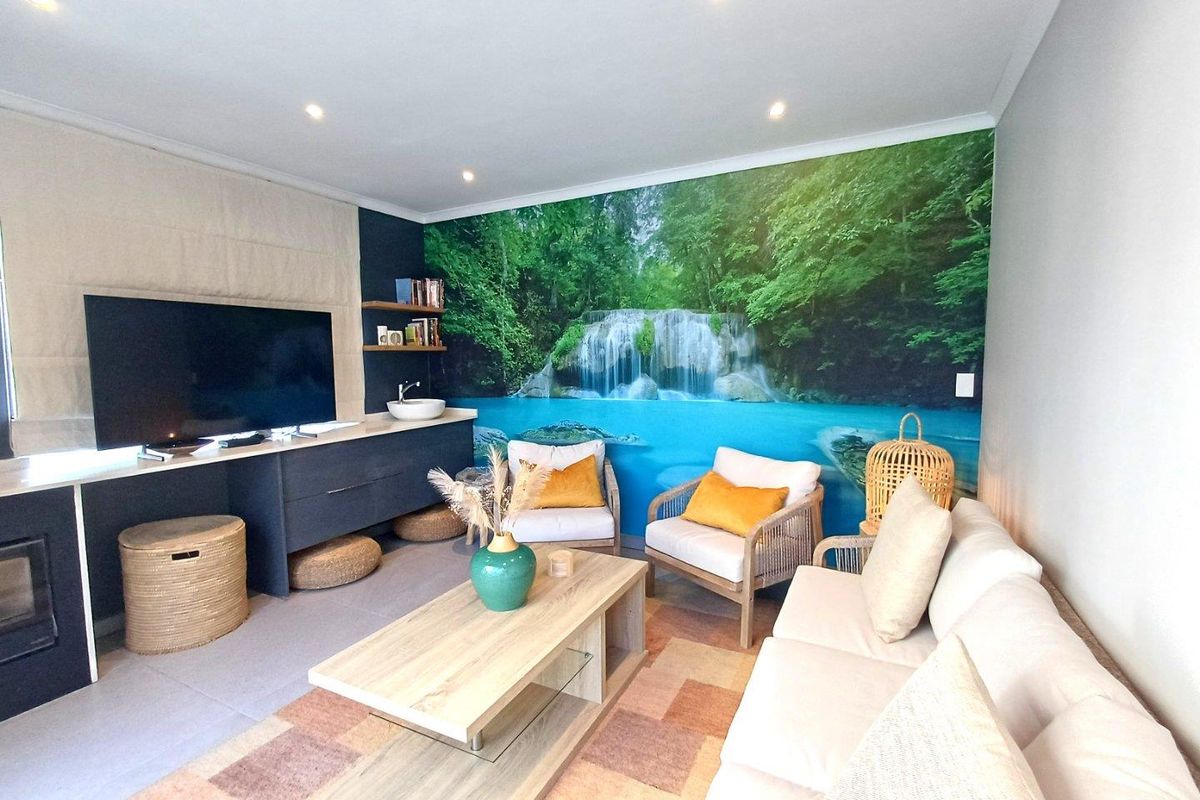 A comfortable living room featuring recessed ceiling lighting, a built-in media console with a sink, and a large nature-themed feature wall mural.