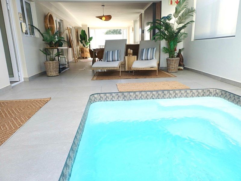 A covered patio area featuring a built-in swimming pool with mosaic tile detailing, providing a seamless transition between indoor and outdoor living spaces.