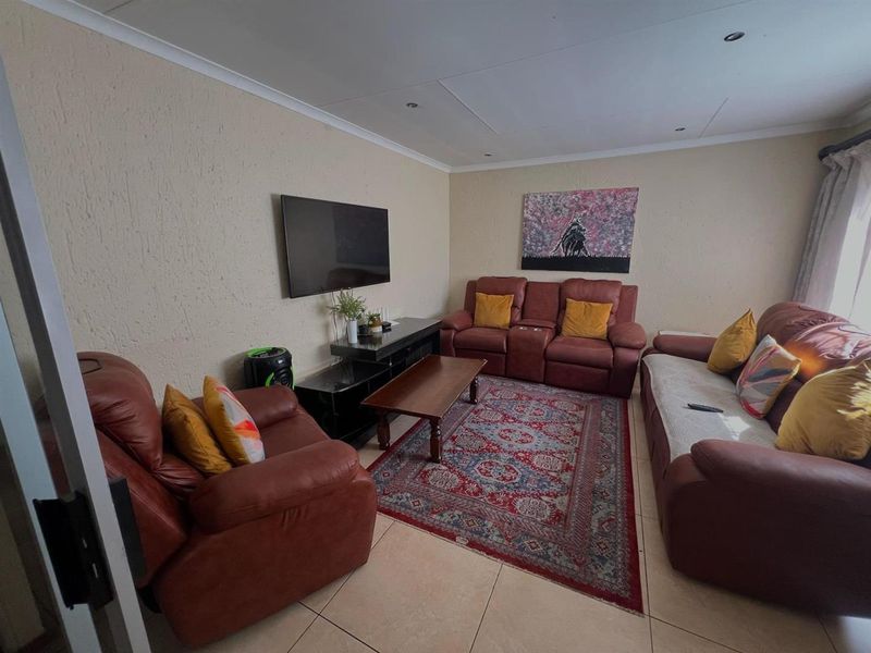 A living room featuring tiled flooring, textured walls, and recessed ceiling lighting, providing a functional space for relaxation.