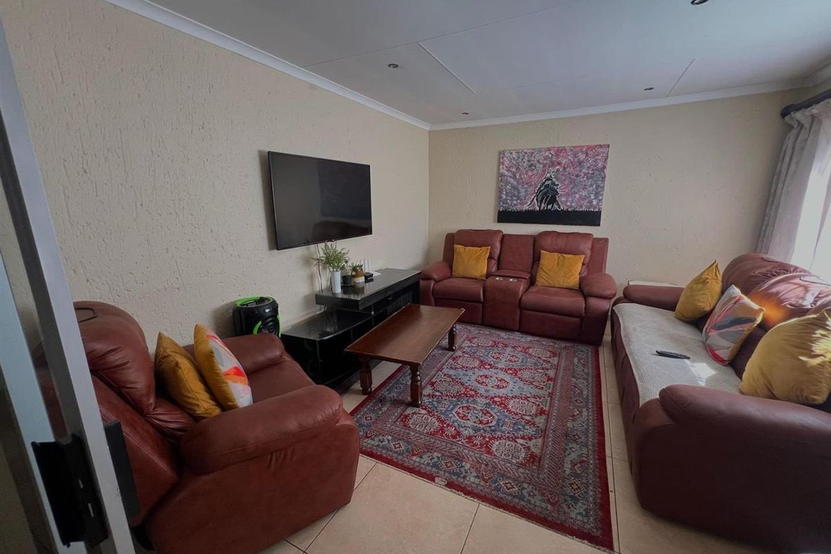 A living room featuring tiled flooring, textured walls, and recessed ceiling lighting, providing a functional space for relaxation.
