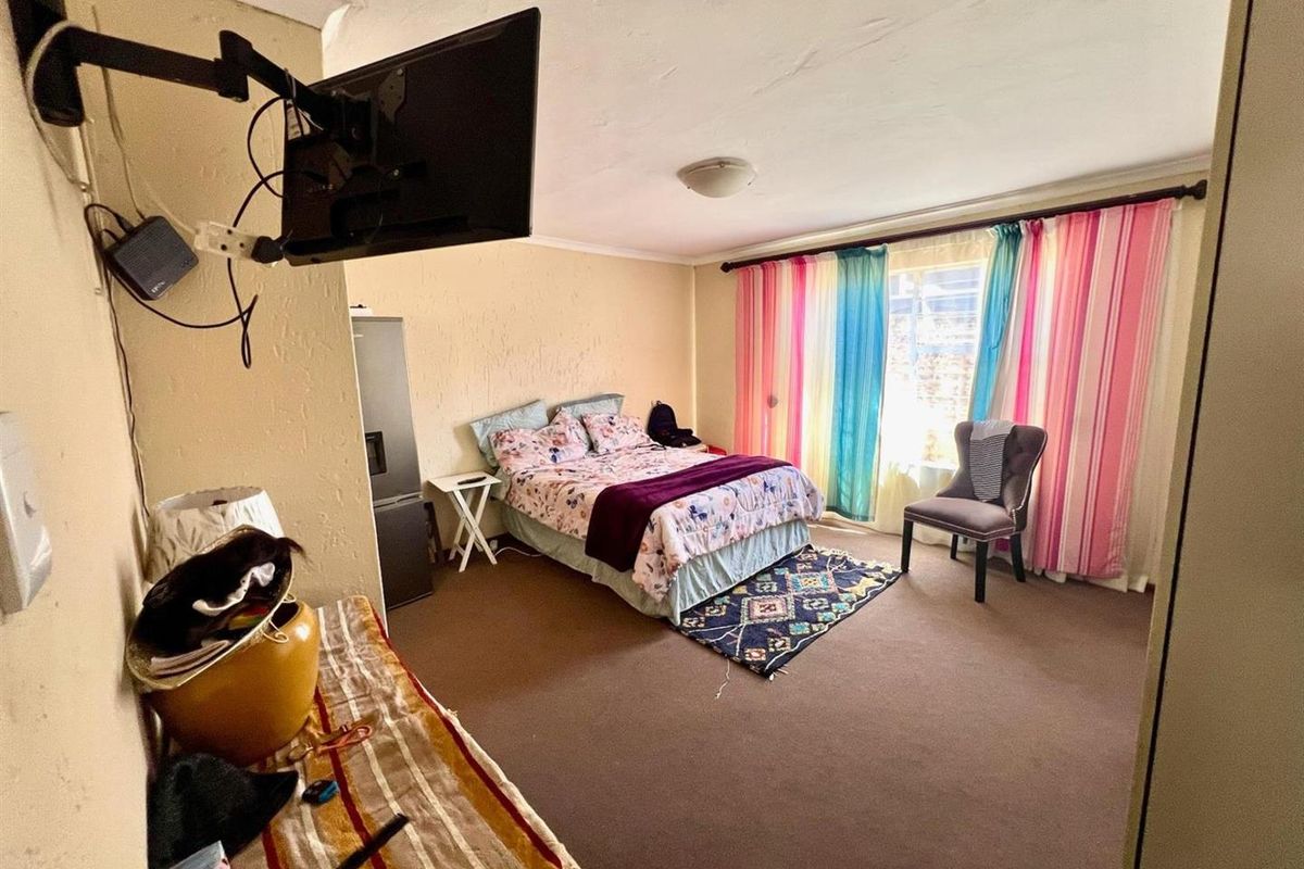 A bedroom featuring carpeted flooring and a window with curtain fixtures, providing a functional sleeping space with potential for cosmetic updates.
