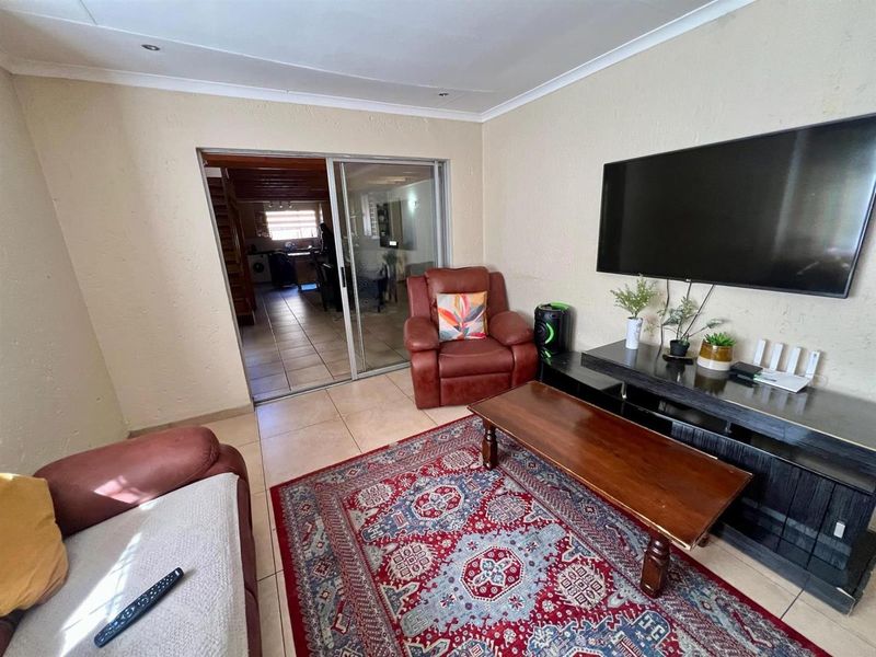 A living room featuring tiled flooring and a sliding glass door providing access to an adjacent room.