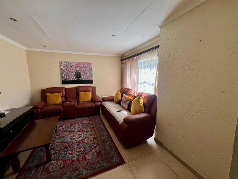 A comfortable living room featuring tiled flooring, recessed ceiling lighting, and a textured wall finish, providing a functional space for relaxation.
