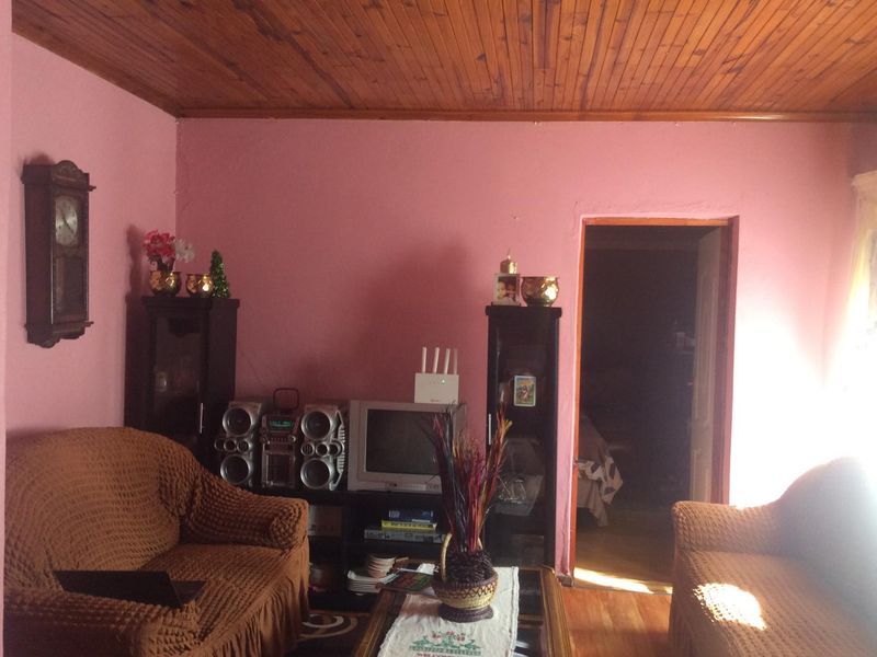 A living room featuring timber tongue and groove ceiling paneling and timber flooring, providing a traditional foundation for potential modern updates.