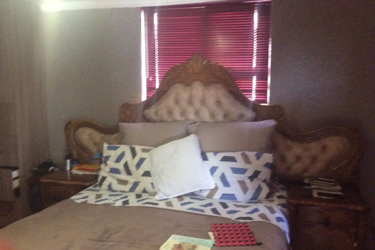 A bedroom featuring crown molding and venetian blinds, providing a functional space for rest.