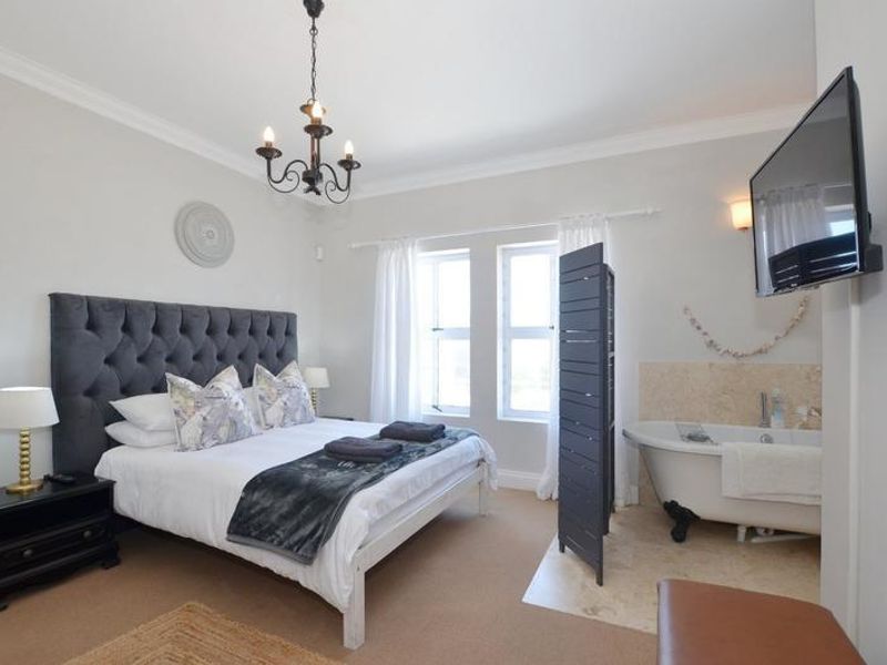 Spacious bedroom featuring a classic claw-foot bathtub integrated into the room layout, complemented by neutral finishes and elegant crown molding.