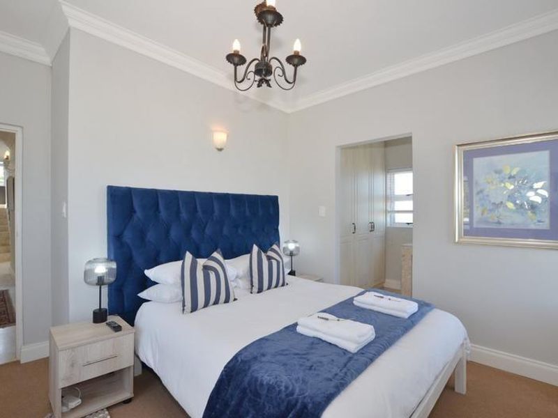 A well-maintained bedroom featuring crown molding, a chandelier, and an adjoining walk-in closet area with built-in cabinetry.