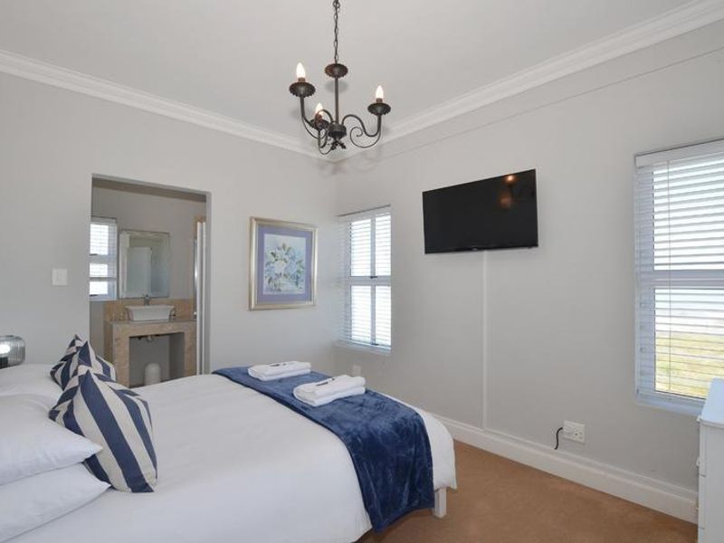 A well-maintained bedroom featuring neutral walls, crown molding, and an en-suite bathroom with a modern vessel sink.