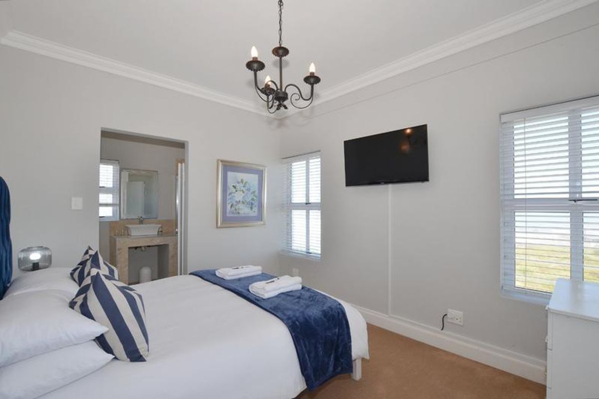 A well-maintained bedroom featuring neutral walls, crown molding, and an en-suite bathroom with a modern vessel sink.