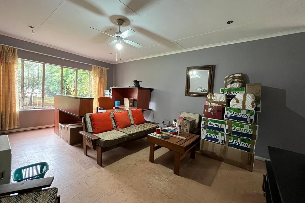 A spacious living room featuring large windows, a ceiling fan, and tiled flooring, offering a blank canvas for renovation and interior design updates.