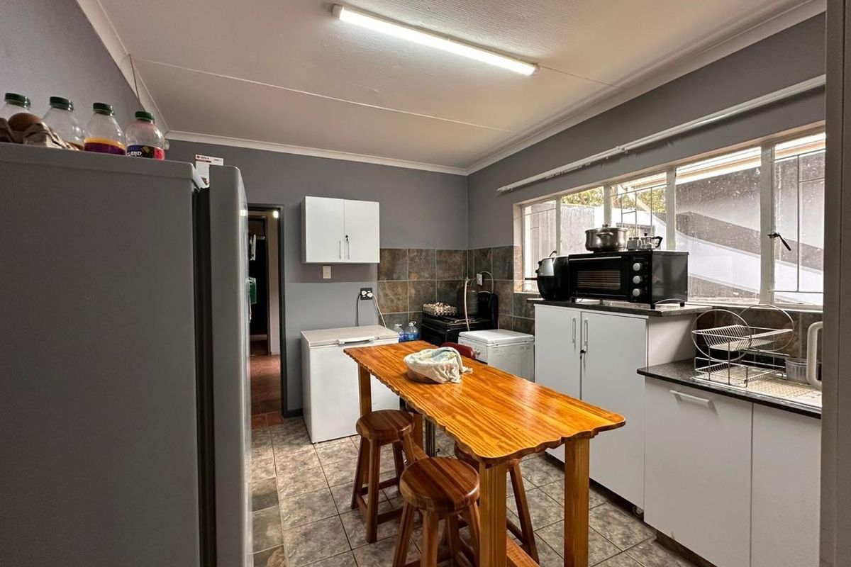 Functional kitchen featuring tiled flooring, built-in cabinetry, and a large window providing natural light, suitable for daily meal preparation.
