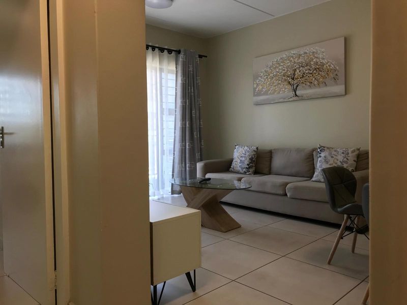 A view into a living room featuring tiled flooring and a sliding glass door leading to an outdoor area.