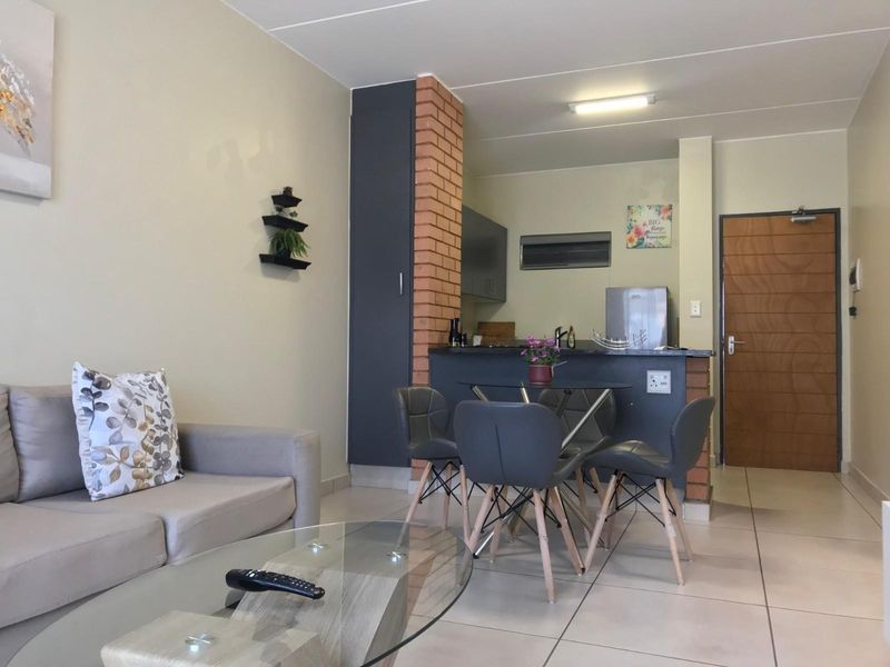 Open plan living and dining area featuring tiled flooring, a breakfast counter, and a functional kitchen layout.