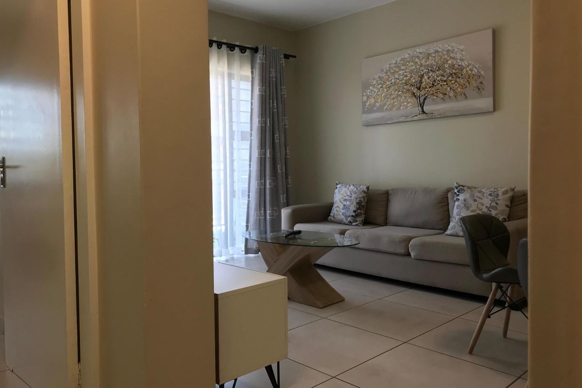 A view into a living room featuring tiled flooring and a sliding glass door leading to an outdoor area.
