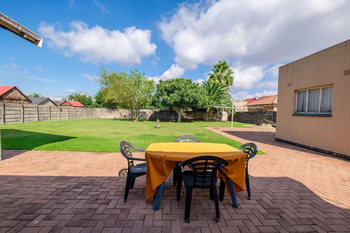 Spacious rear garden featuring a paved patio area, expansive lawn, and secure perimeter walling, ideal for outdoor relaxation and entertaining.