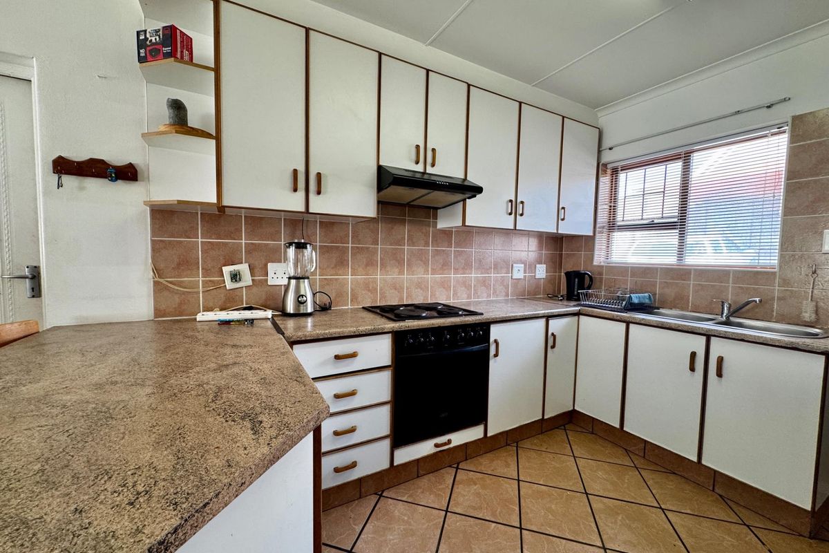 A functional kitchen featuring white cabinetry, a built-in oven and hob, tiled backsplash, and a breakfast bar counter.