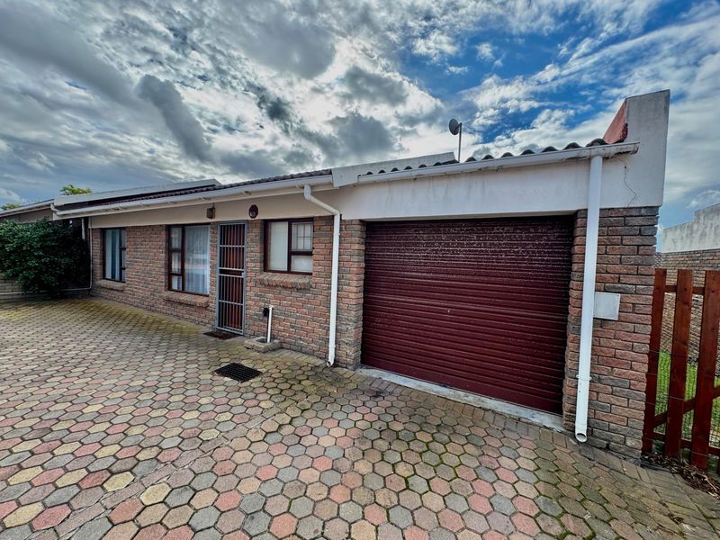 Front exterior view of the property featuring a face-brick facade, a single roller-shutter garage door, and a paved driveway area.