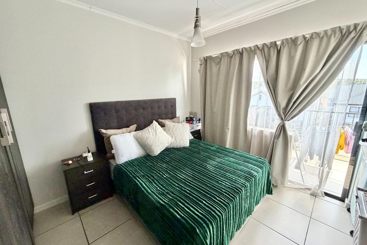 A bedroom featuring tiled flooring, a pendant light, and a sliding glass door providing access to an outdoor balcony area.