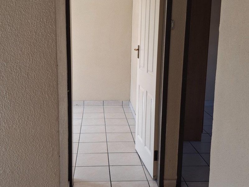 A view through a doorway into an adjacent tiled room, featuring neutral wall finishes and standard door frames.