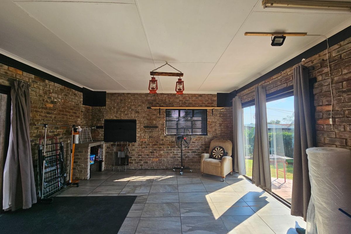 Spacious living area featuring exposed face-brick walls, tiled flooring, and large sliding glass doors providing direct access to the garden.