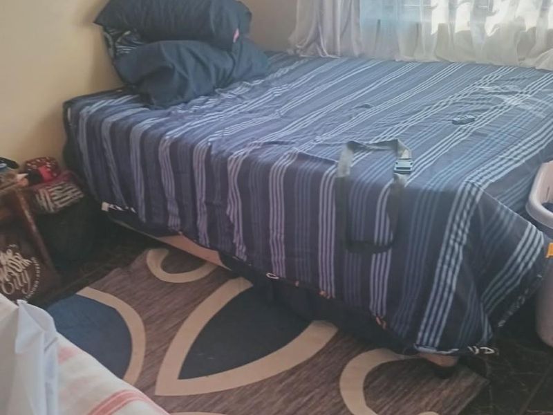 A bedroom featuring tiled flooring and a window with curtains, providing a functional sleeping space.