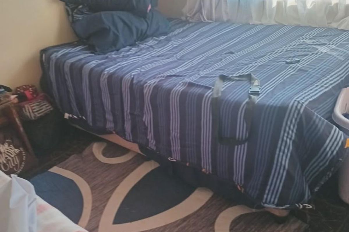 A bedroom featuring tiled flooring and a window with curtains, providing a functional sleeping space.