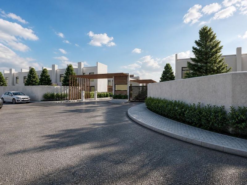 A modern residential estate entrance featuring a paved driveway, perimeter boundary walls, and a timber-slatted gate structure.